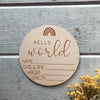A round wooden sign with the words Hello World and lines for name, date & time, weight, and length, featuring a rainbow desig