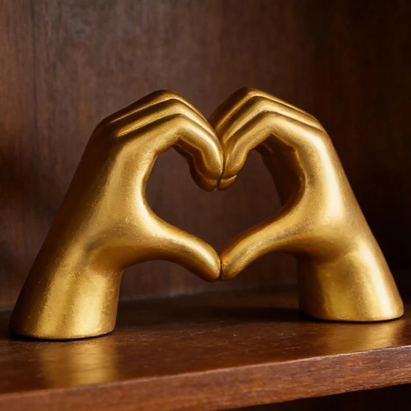 A golden sculpture of two hands forming a heart shape, used as romantic love decor.