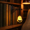 An antique library lantern with a yellow glow hangs in front of a wooden bookshelf filled with old books.