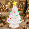 A white ceramic Christmas tree decorated with multicolor LED lights, set in a snowy holiday scene.