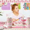 A woman is preparing a craft project with a set of retro floral themed washi tape rolls on a table.