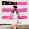 A person wearing a striped jacket stands in front of an American flag banner.