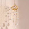 A hanging gold flame moon crystal sun catcher with dangling clear and colored crystals.