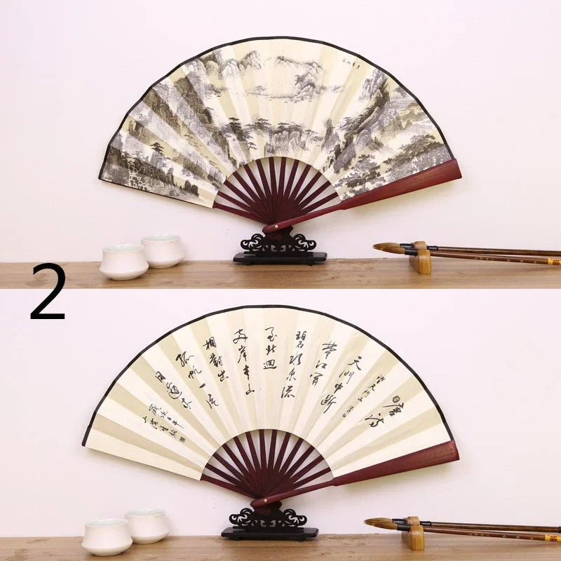 A pair of retro folding silk and bamboo decorative fans displayed on a wooden surface.