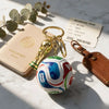 A gold-colored FIFA trophy keychain attached to a soccer ball, resting on a passport and boarding pass.