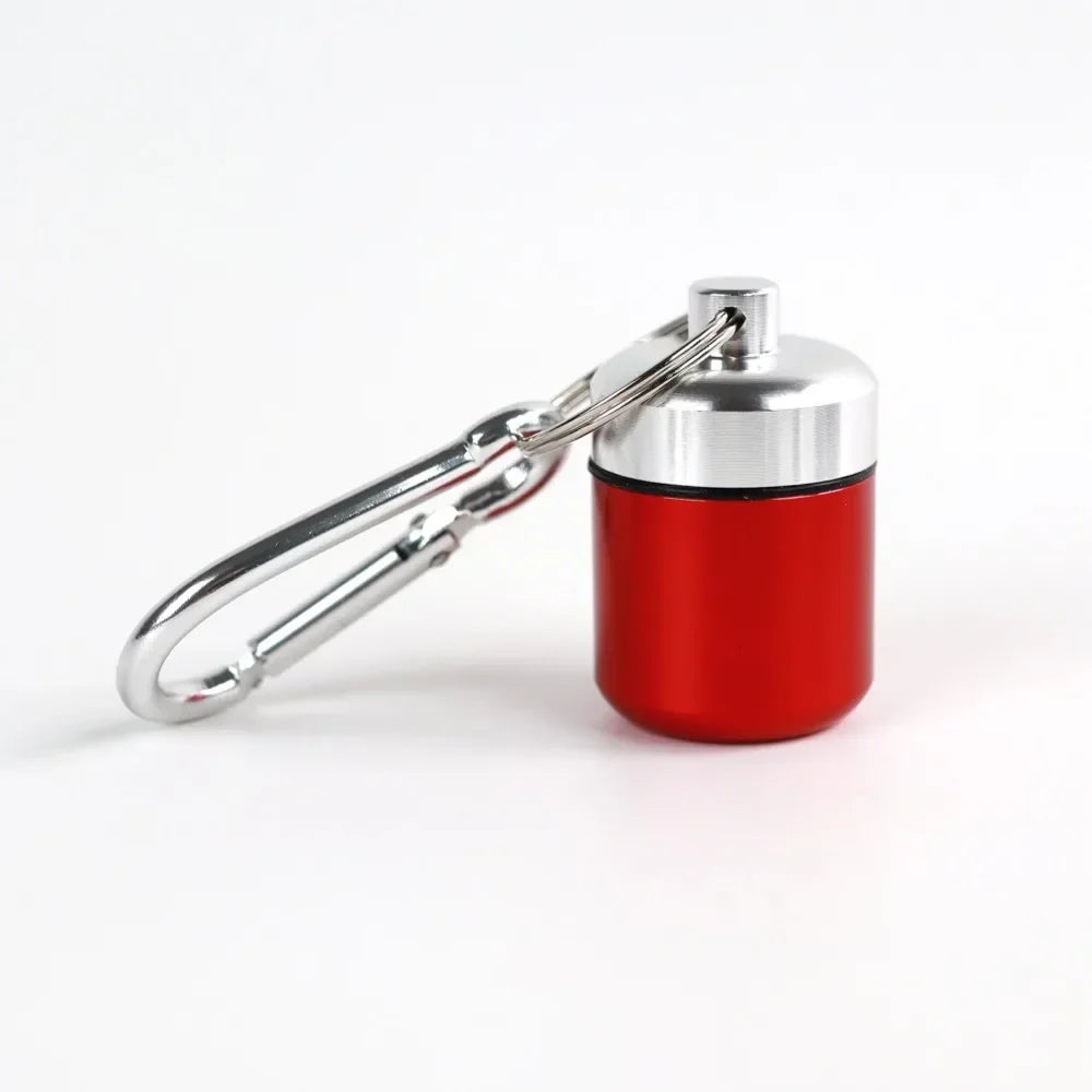 A small red and silver pill organizer is attached to a metal keyring.