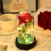 Ein Glasgefäß mit einer roten Rose und leuchtenden LED-Lichtern auf einer schwarzen Basis.