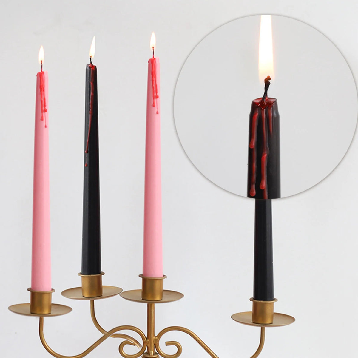 Set of four black and pink taper candles with dripping blood effect displayed on a gold stand.
