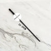 A black metal magic wand replica with a circular label indicating the metal core on a white marble surface.