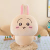 A soft, light beige Usagi Chiikawa plush doll with pink ears sitting on a woven mat.