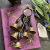 A set of decorative metal wind chimes with a leather cord and ornate hook displayed on a purple book.