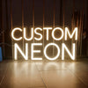 A glowing custom neon sign spelling out CUSTOM NEON on a wooden floor.
