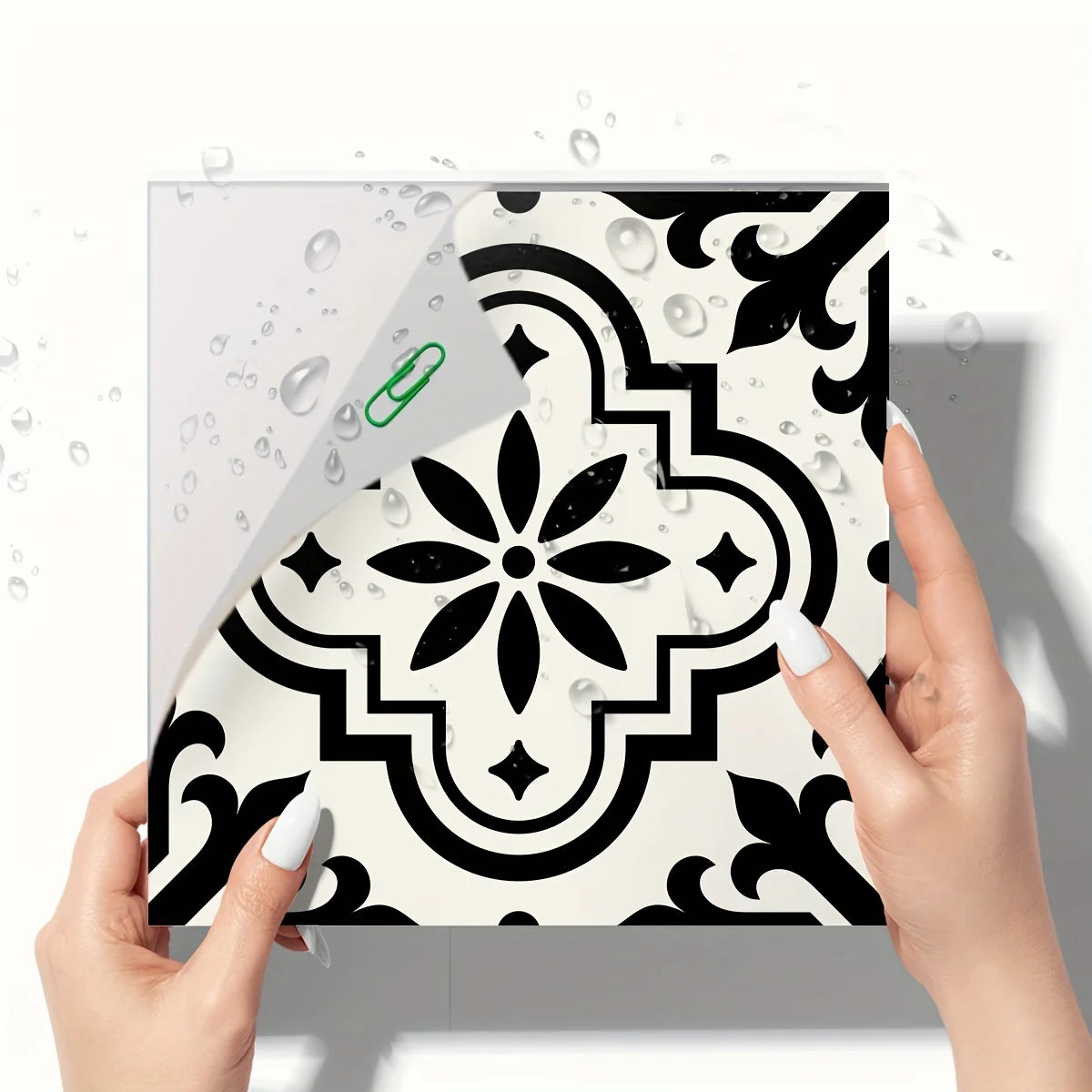 A hand holds a sheet of Moroccan pattern floor stickers featuring black and white geometric designs.