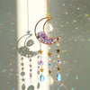 A hanging moon-shaped crystal suncatcher featuring a purple amethyst crescent and sparkling prism elements.