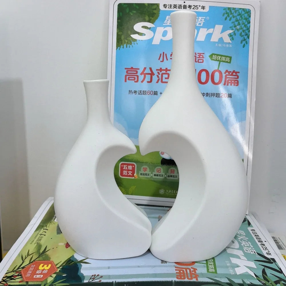 A white ceramic vase shaped like a heart is displayed in front of a sign advertising Spark products.