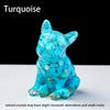 A turquoise crystal dog statue with small cracks sits on a white surface.