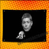 A black and white portrait of a man is displayed on a yellow polka-dot background.
