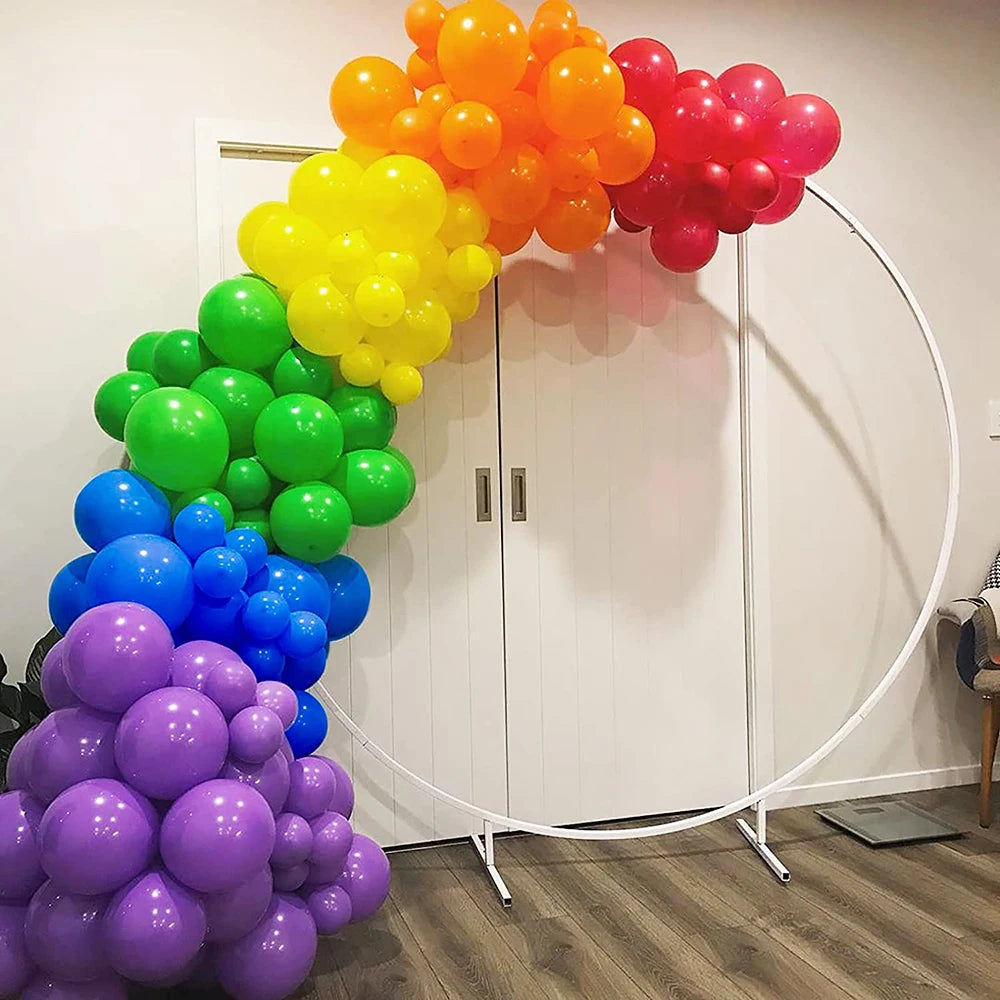 A vibrant balloon garland arch featuring rainbow colors like orange, yellow, green, blue, and pink clustered together.