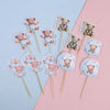 A collection of cute cartoon bear cupcake toppers on wooden sticks in pastel pink and blue colors.