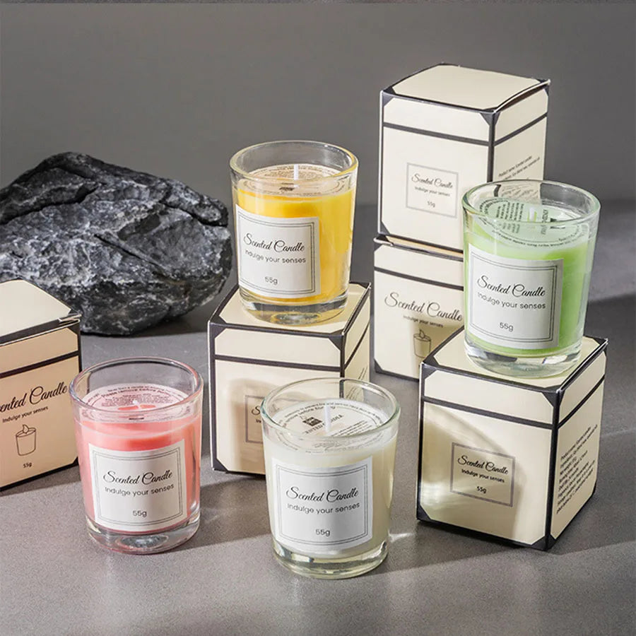 A collection of scented candles in glass jars and boxes, featuring yellow, green, and pink scents.