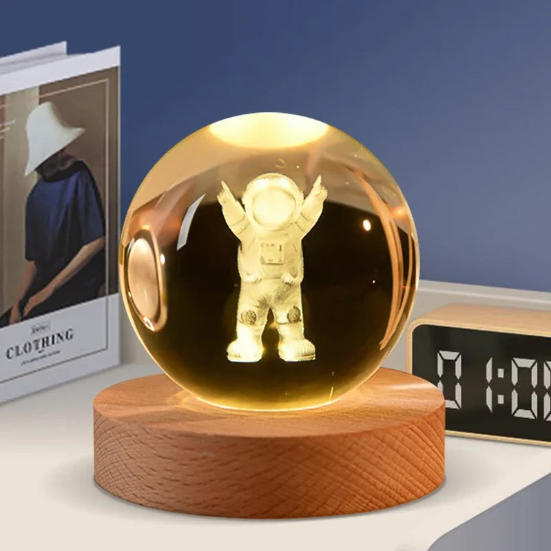 A golden crystal ball decoration with a figure inside, resting on a wooden base.