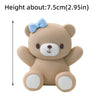 A light brown teddy bear block topper with a blue bow and white paws.