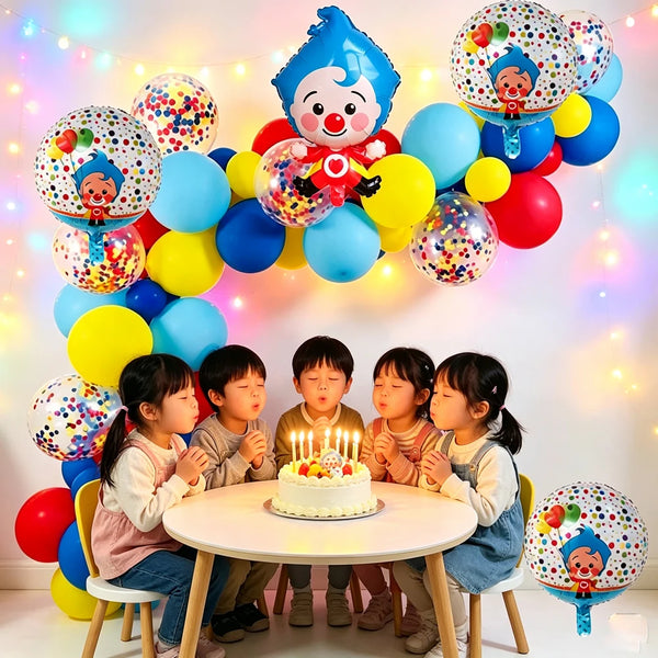 A table is decorated with a colorful balloon arch featuring cartoon clown designs and balloons for a party.