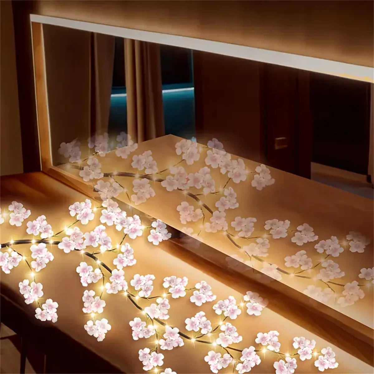 LED rattan string lights with pink flowers decorating a wooden surface.