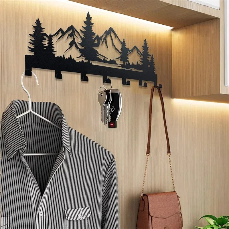 A black metal key holder with hooks mounted on a wall above a striped shirt.