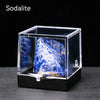 A clear glass box displaying a rough blue and white crystal specimen on a black base.