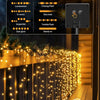 Outdoor fairy string lights with various lighting modes displayed on a panel, illuminating a wooden fence.