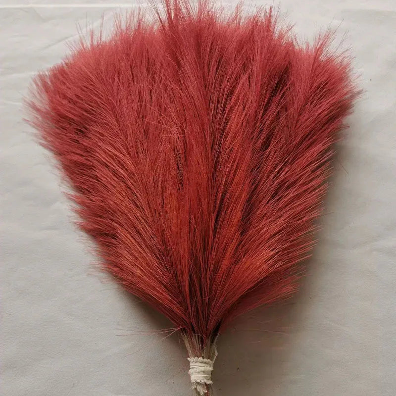 A vibrant reddish-orange artificial pampas grass bouquet used for boho home decor.