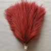A vibrant reddish-orange artificial pampas grass plume used for boho wedding and home decor.