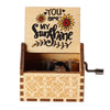 Handaufzugswundwerk mit Deckel, auf dem der Text „You are my sunshine“ und florale Designs zu sehen sind.