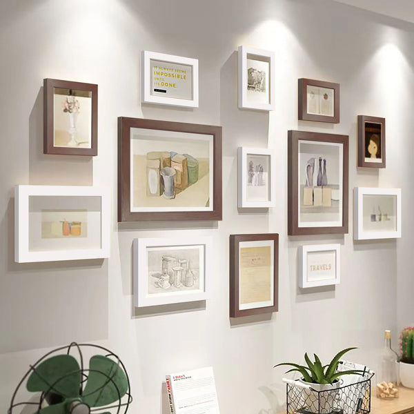 A collection of thirteen wooden picture frames in various sizes and tones displayed on a light gray wall.