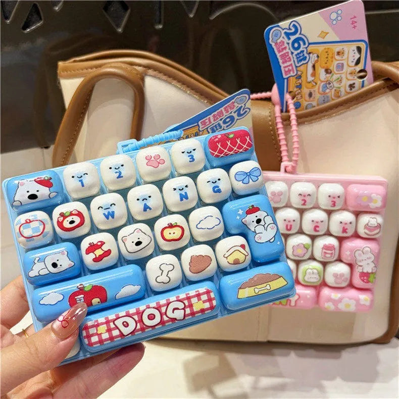 A hand holds a blue cartoon animal keyboard keycap fidget toy with various animal shapes and a pink keychain in a beige bag.