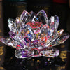 A clear crystal lotus flower ornament with pink and purple facets resting on a dark surface.