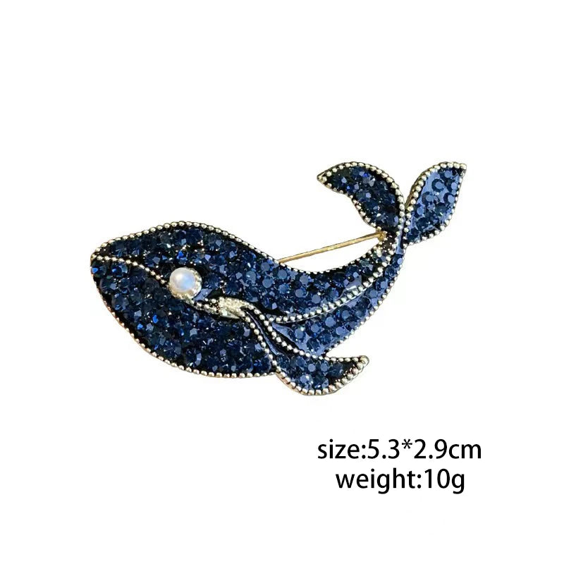 A vintage marine life brooch pin featuring a dark blue fish design adorned with sparkling blue stones.