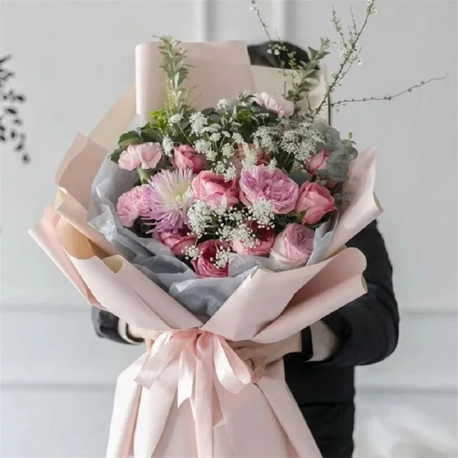 A bouquet of pink and white flowers wrapped in soft tissue paper for gift wrapping