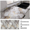 A black kitchen sink installed on a marble countertop featuring gold leaf veining and adhesive backing.