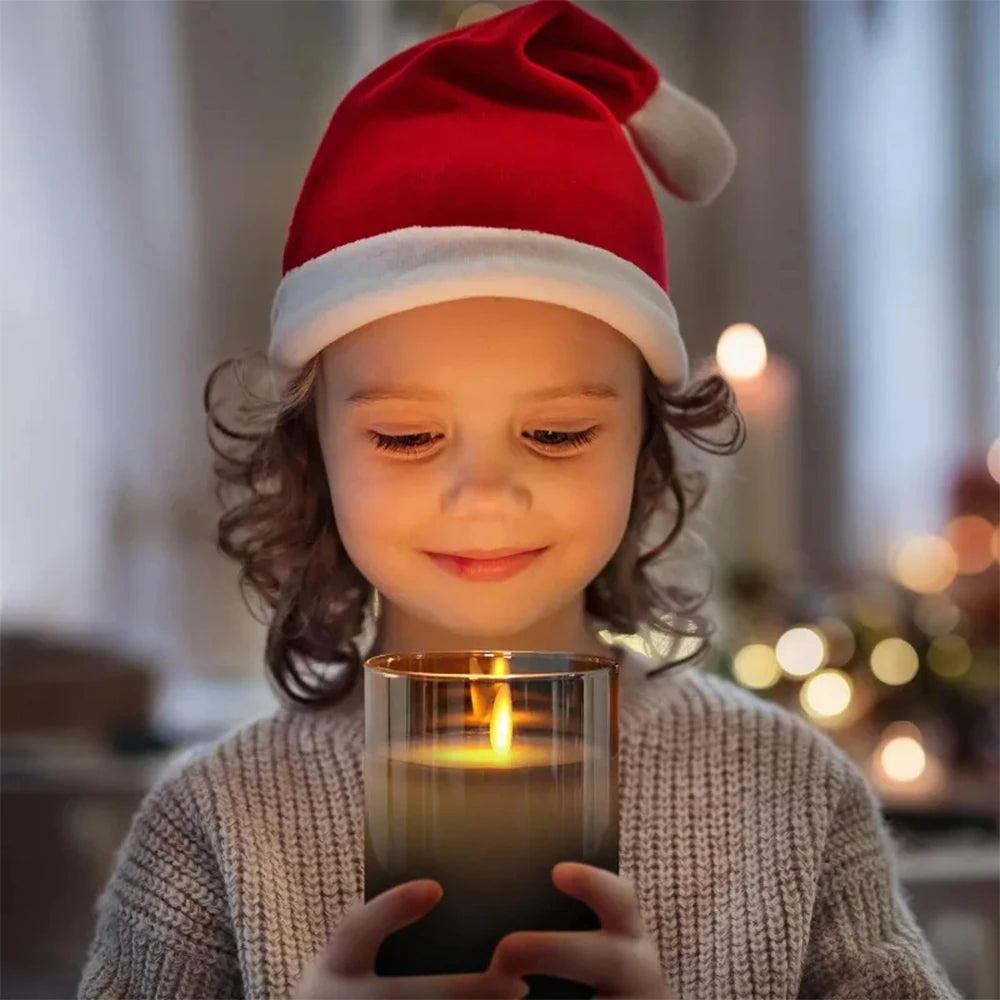 A young child wearing a Santa hat holds a glowing LED flameless candle in a cozy setting.