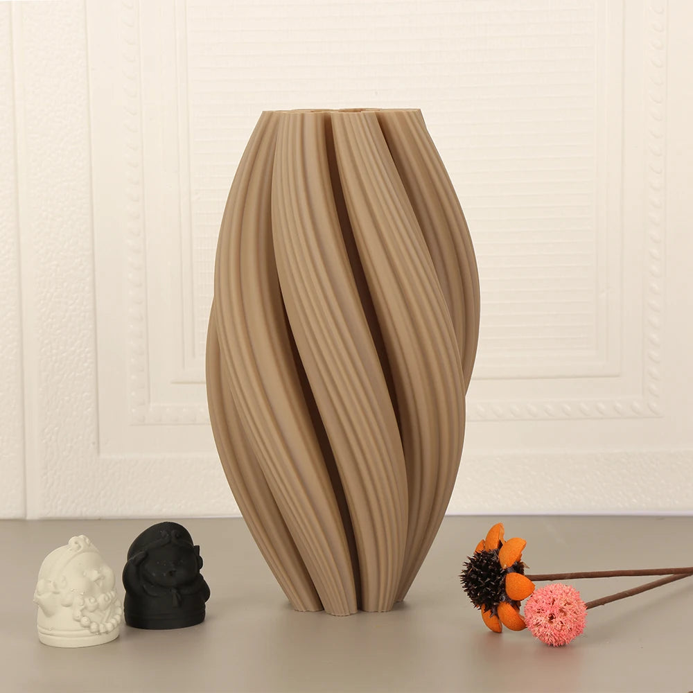 A textured wave vase in soft morandi tones sits on a surface next to small decorative objects.