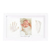 A framed photo showing a baby's handprint and footprint inside a white picture frame.
