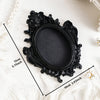 Black ornate resin wall decor pendant with a decorative frame and oval center.