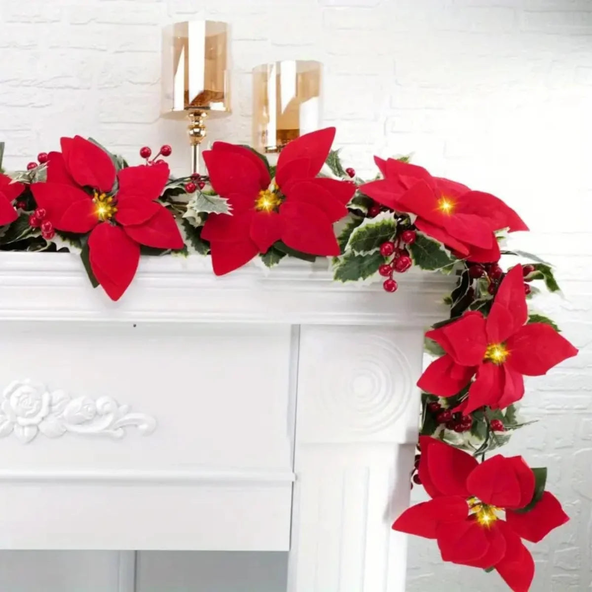 A vibrant red poinsettia garland featuring faux flowers and greenery displayed on a white mantelpiece.