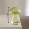Un vase décoratif en verre transparent en forme de champignon avec un large chapeau et un corps arrondi, sur fond blanc.