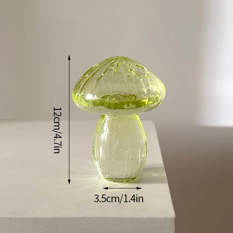 Un vase décoratif en verre transparent en forme de champignon avec un large chapeau et un corps arrondi, sur fond blanc.