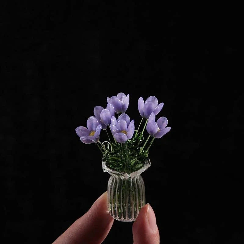 A hand holds a small glass vase filled with purple lavender flowers against a dark background.