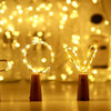 A set of ten LED wine bottle cork lights glowing brightly on a wooden surface.