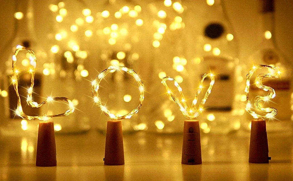 A set of ten LED wine bottle cork lights glowing brightly on a wooden surface.